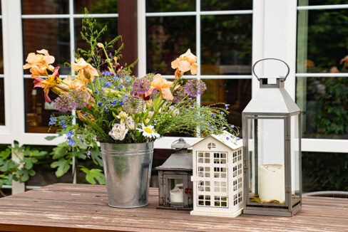 Ein Holztisch mit Blumenstrauß und Kerzenhaltern - Jetzt Immobilie kaufen