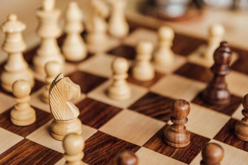Holzschachfiguren auf einem Schachbrett als Symbol für Strategie und Taktik beim Bieterverfahren im Immobilienkauf | Bieterverfahren
