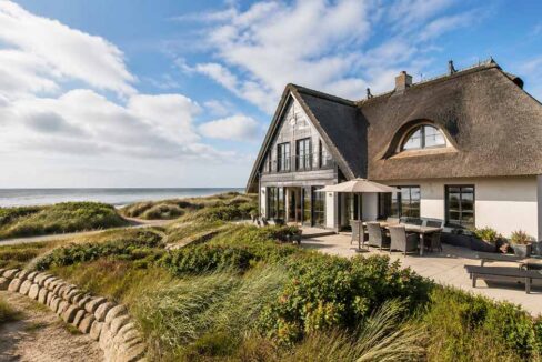 Ferienhaus mit Reetdach in Dünenlage am Meer – Symbolbild für den Verkauf einer Ferienimmobilie. | Immobilienverkauf